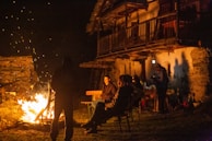 Family and friends gathered around a campfire near the cozy hunting cabin at dusk.