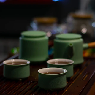 A traditional Japanese tea set on a wooden table with steaming green tea cups.