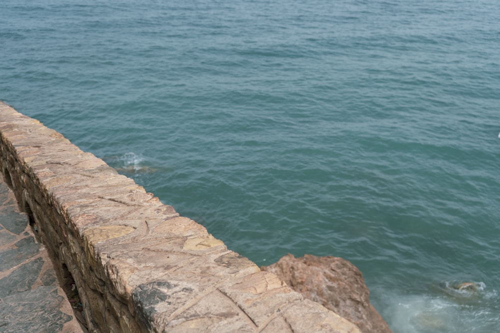 a rock wall with a body of water in the background