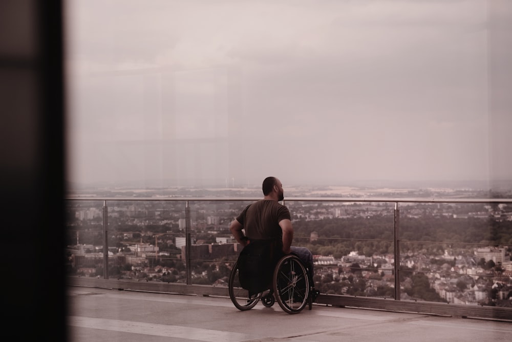 a person in a wheelchair looking out a window at a city