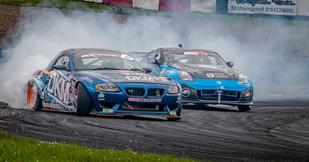 a group of race cars on a track with smoke coming out of the tires