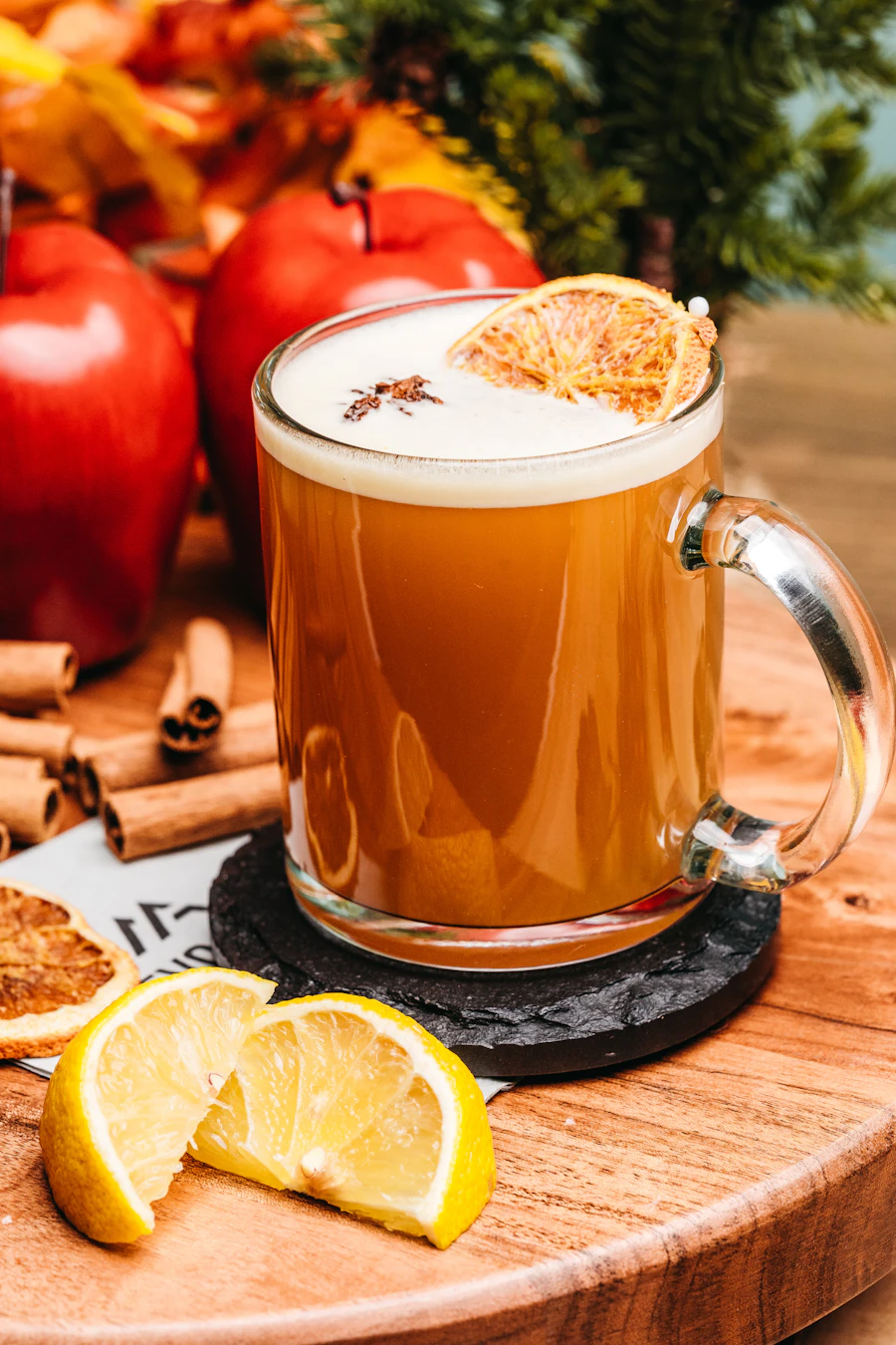 Hot apple cider in a glass mug with apples and cinnamon