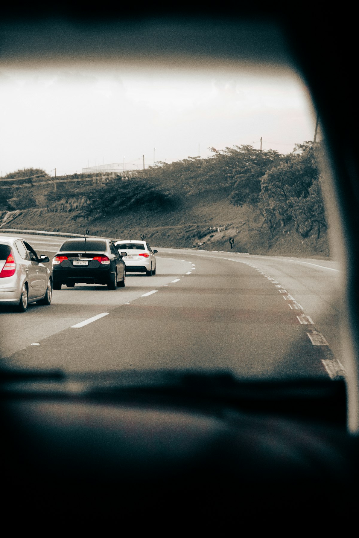 A group of cars driving on a multi-lane highway during the day