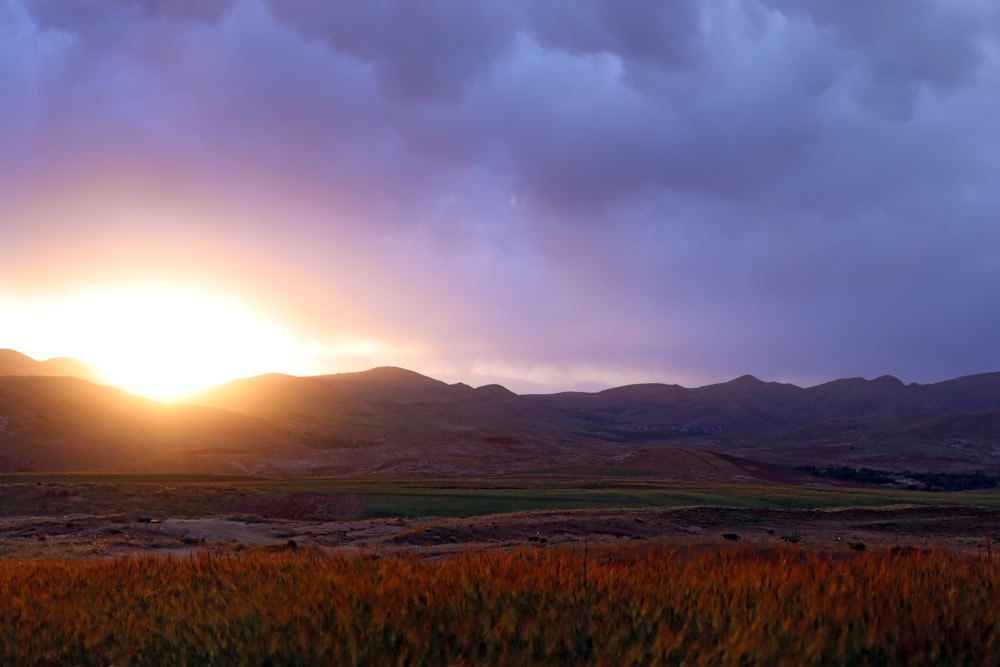 a landscape with hills and a sunset