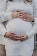 Hands of a doula supporting a mother’s belly during pregnancy, symbolizing care and connection.