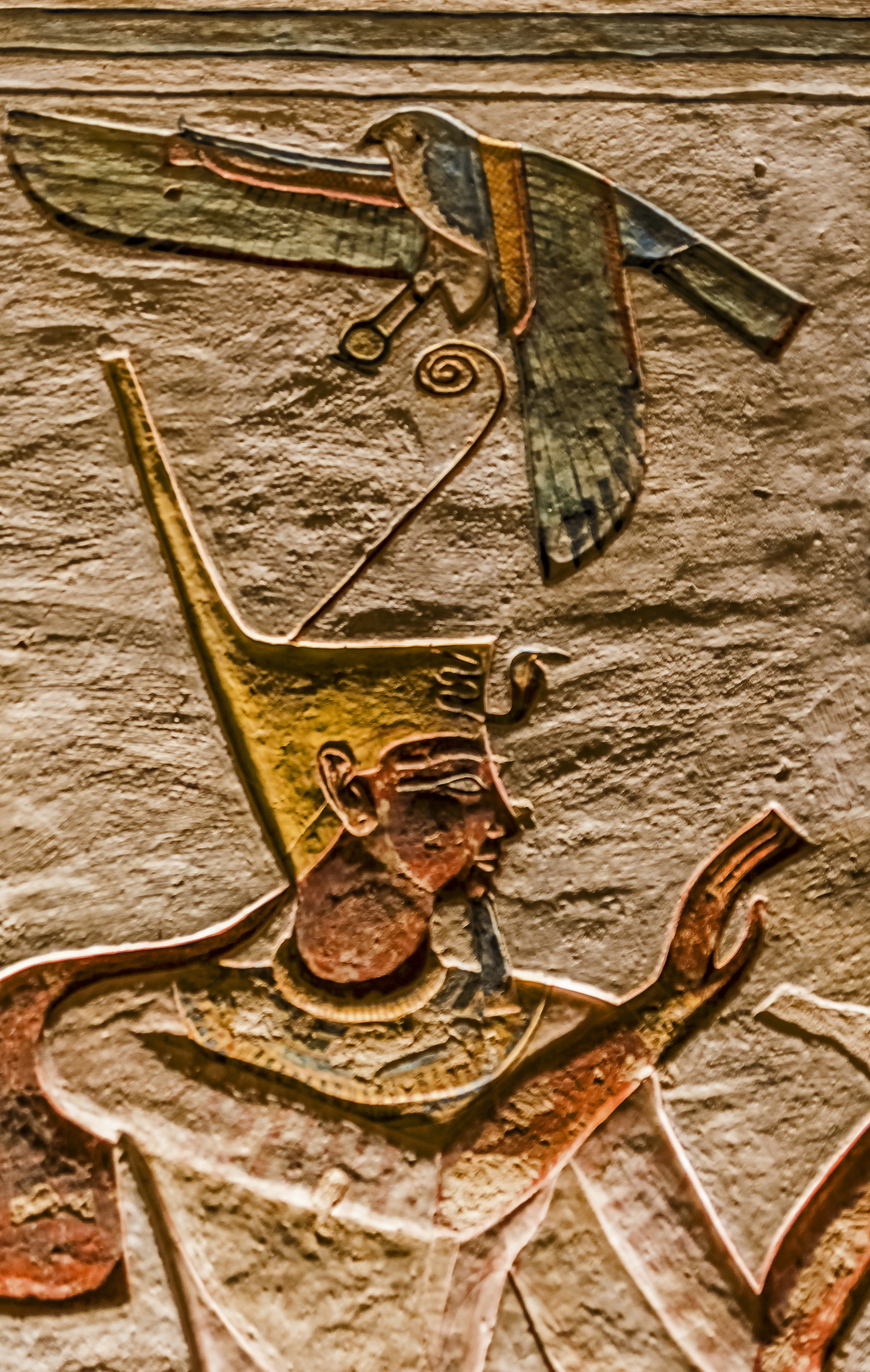 An intricate carving of a pharaoh wearing the traditional headdress, etched into the walls of a temple.