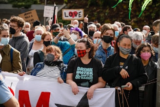 A group of diverse supporters holding banners and smiling during a campaign rally.
