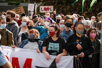 A group of diverse supporters holding banners and smiling enthusiastically at a political rally.