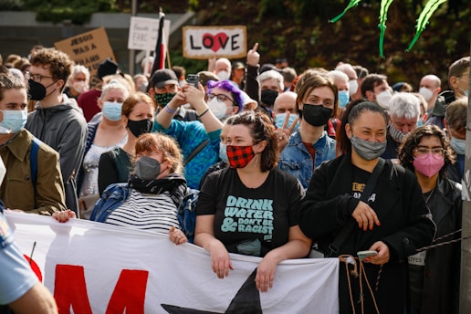 A group of diverse supporters holding banners and smiling during a campaign rally.