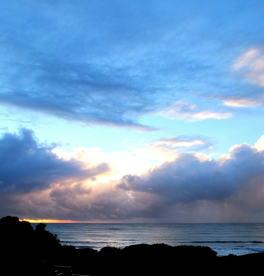 a body of water with clouds above it