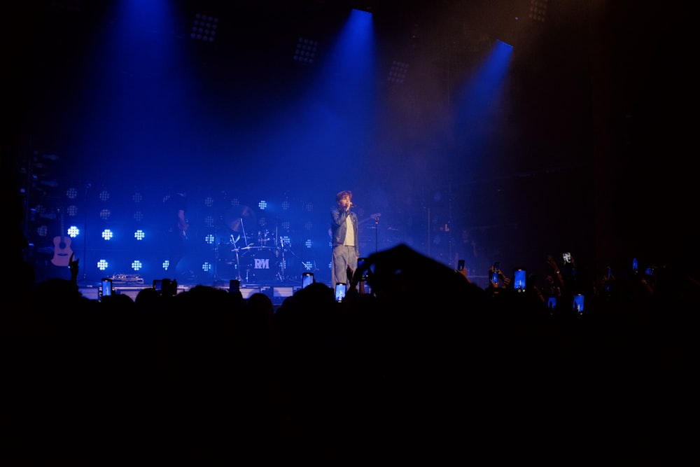 a person on a stage with a microphone and a crowd watching