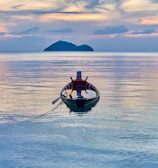A traditional boat anchored by a palm-fringed beach in the Nicobar Islands at sunset