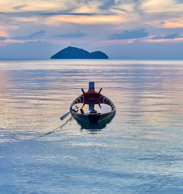 A traditional boat anchored by a palm-fringed beach in the Nicobar Islands at sunset
