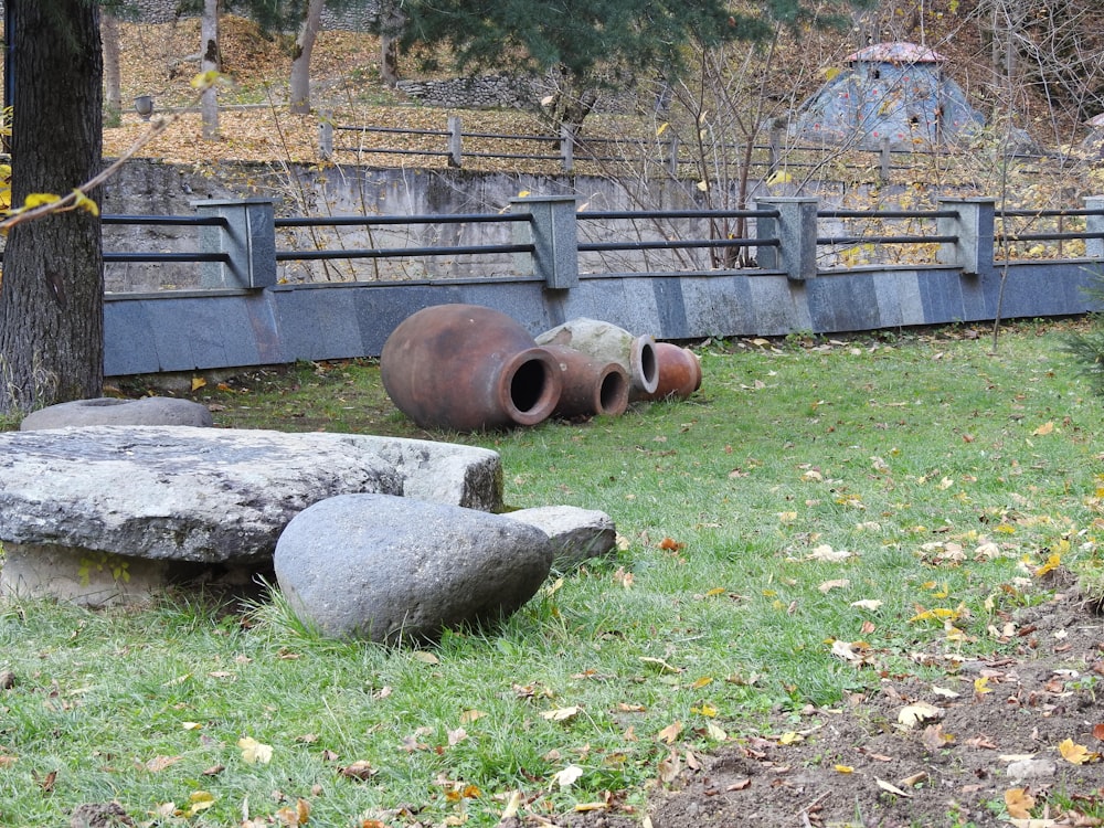 a group of large rocks in a grassy area next to a fence
