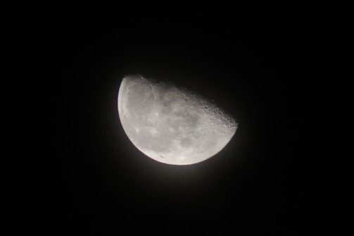 A bright, detailed view of the half-moon set against a stark black background, with visible craters and surface textures on the illuminated portion.
