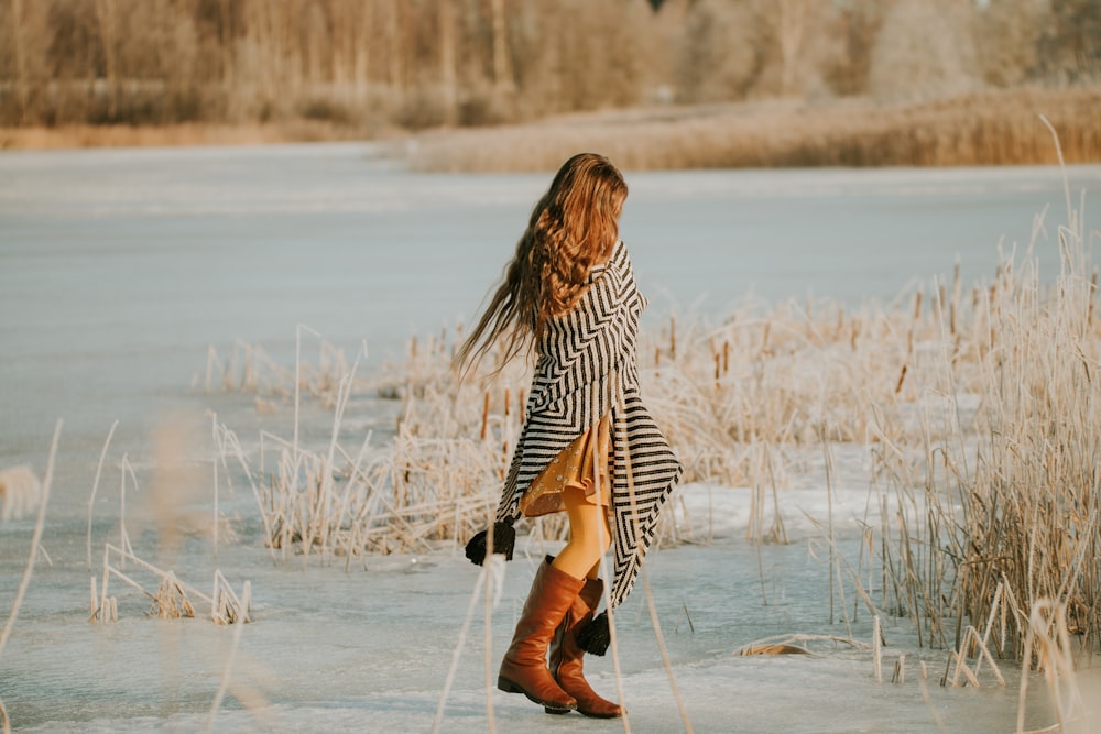 a woman in a striped dress is walking in the snow