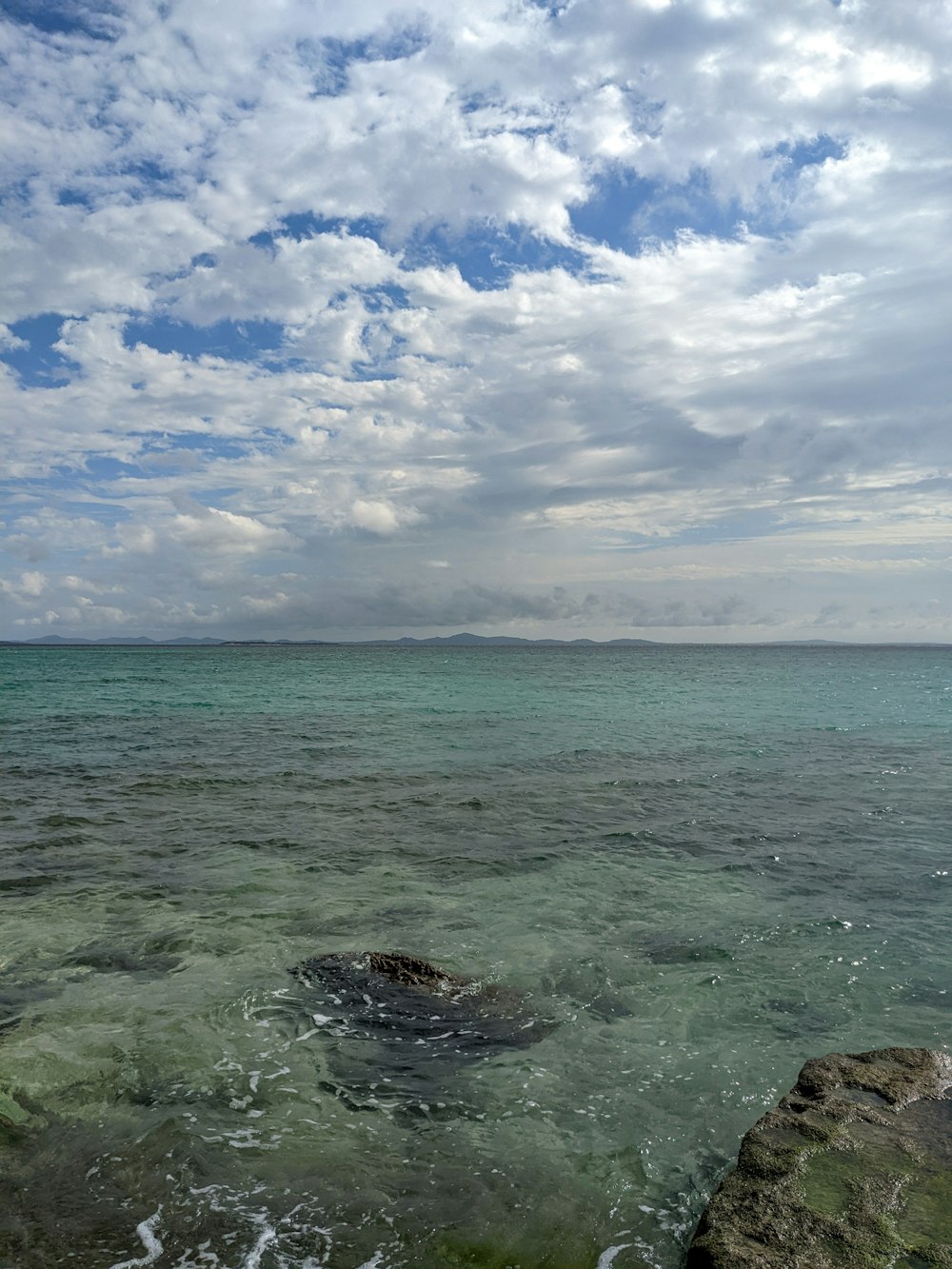 a body of water with rocks and a cloudy sky