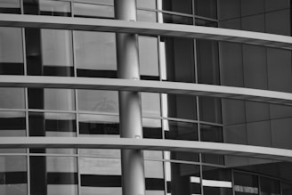 A modern architectural structure featuring multiple horizontal parallel lines and reflective glass panels. The building's facade has a sleek, minimalistic design typical of contemporary urban architecture.