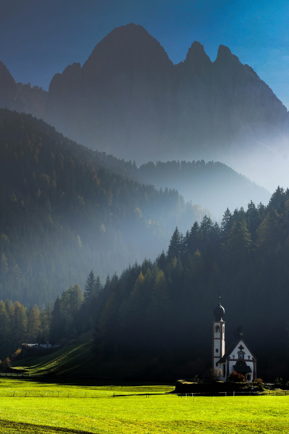 a building in a field with trees and mountains in the background