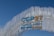 A contemporary art installation with vertical metal rods arranged in a wave pattern forms a striking visual backdrop. The metal rods create a textured appearance against the clear blue sky. Prominent text reads 'COP27 SHARM EL-SHEIKH EGYPT 2022' in bold letters, alternating between blue and gold colors, signifying a significant event.