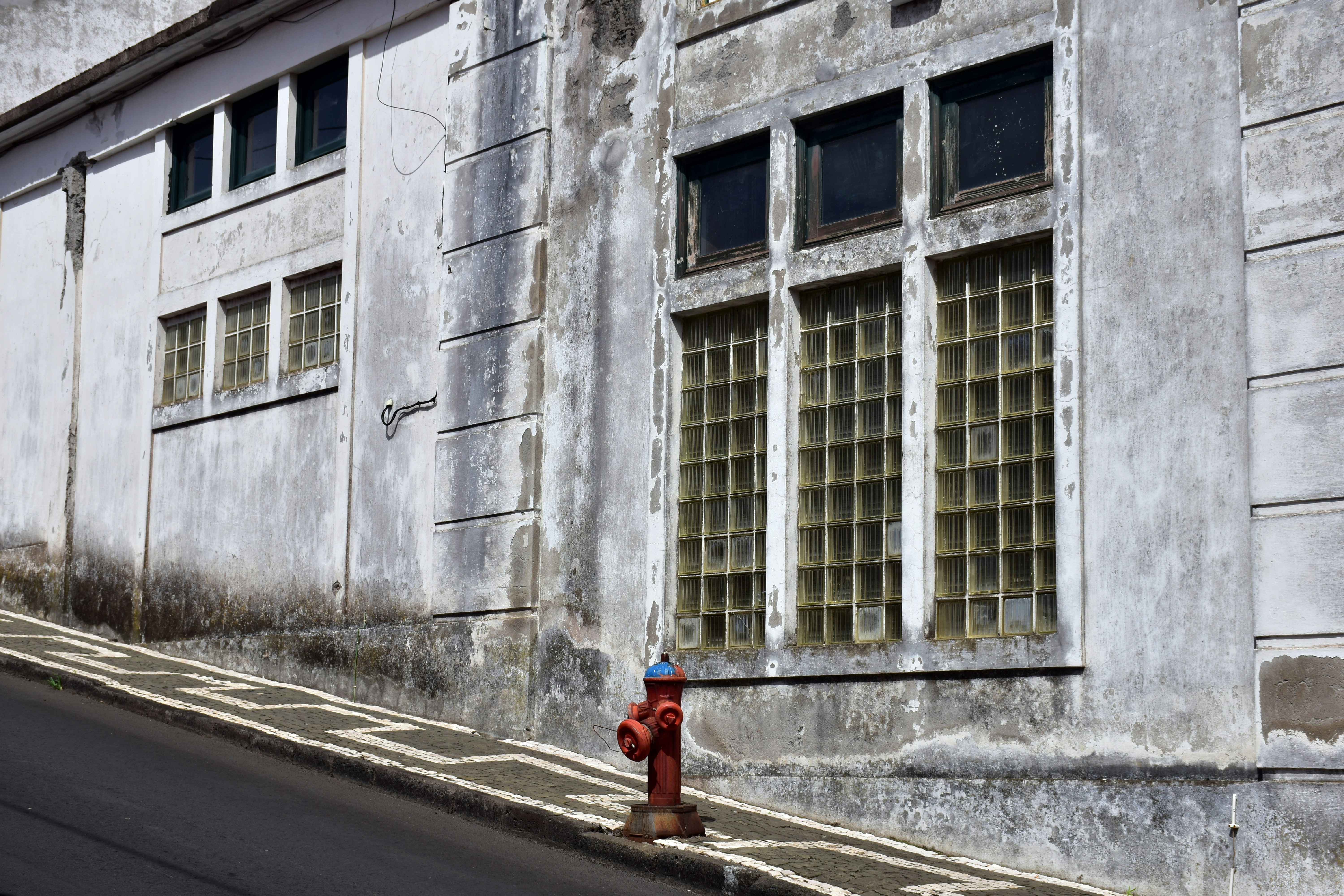 a red fire hydrant on the side of a street, `This part of the building stands out`