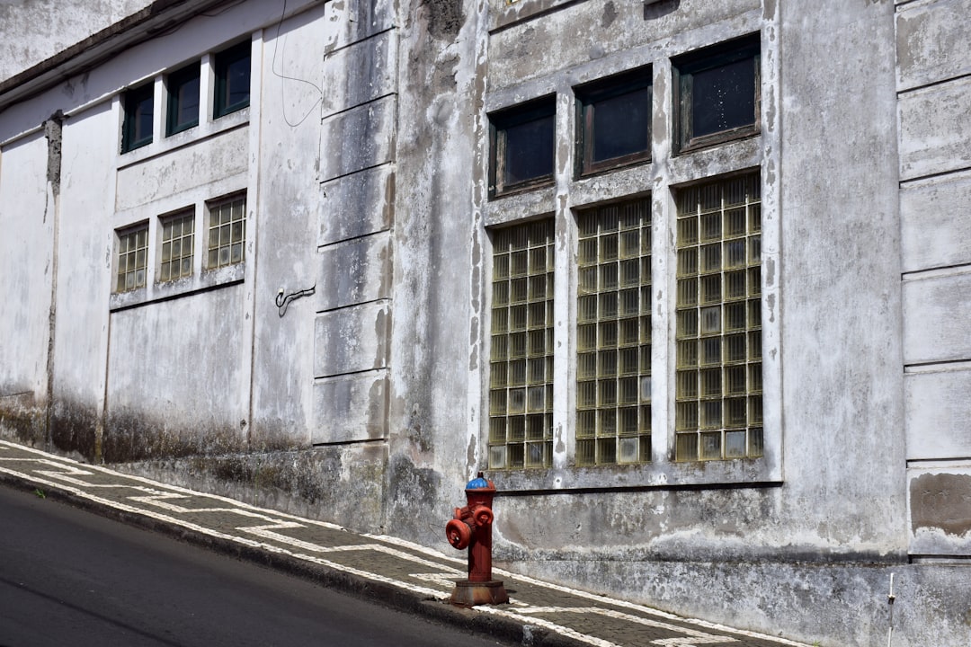 a red fire hydrant on the side of a street, `This part of the building stands out`