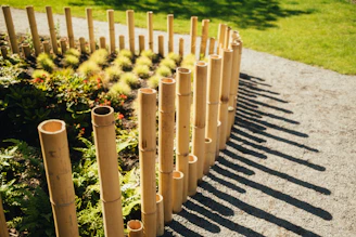 A bamboo post garden border beside a path, with colourful flower bedding and a clean grass edge in t
