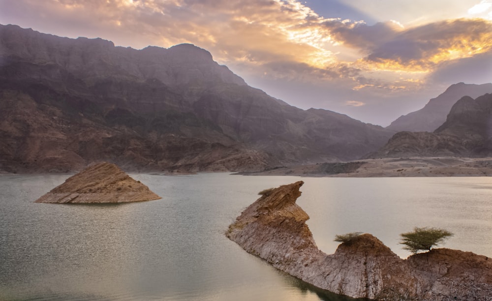 a body of water with rocks and mountains in the background