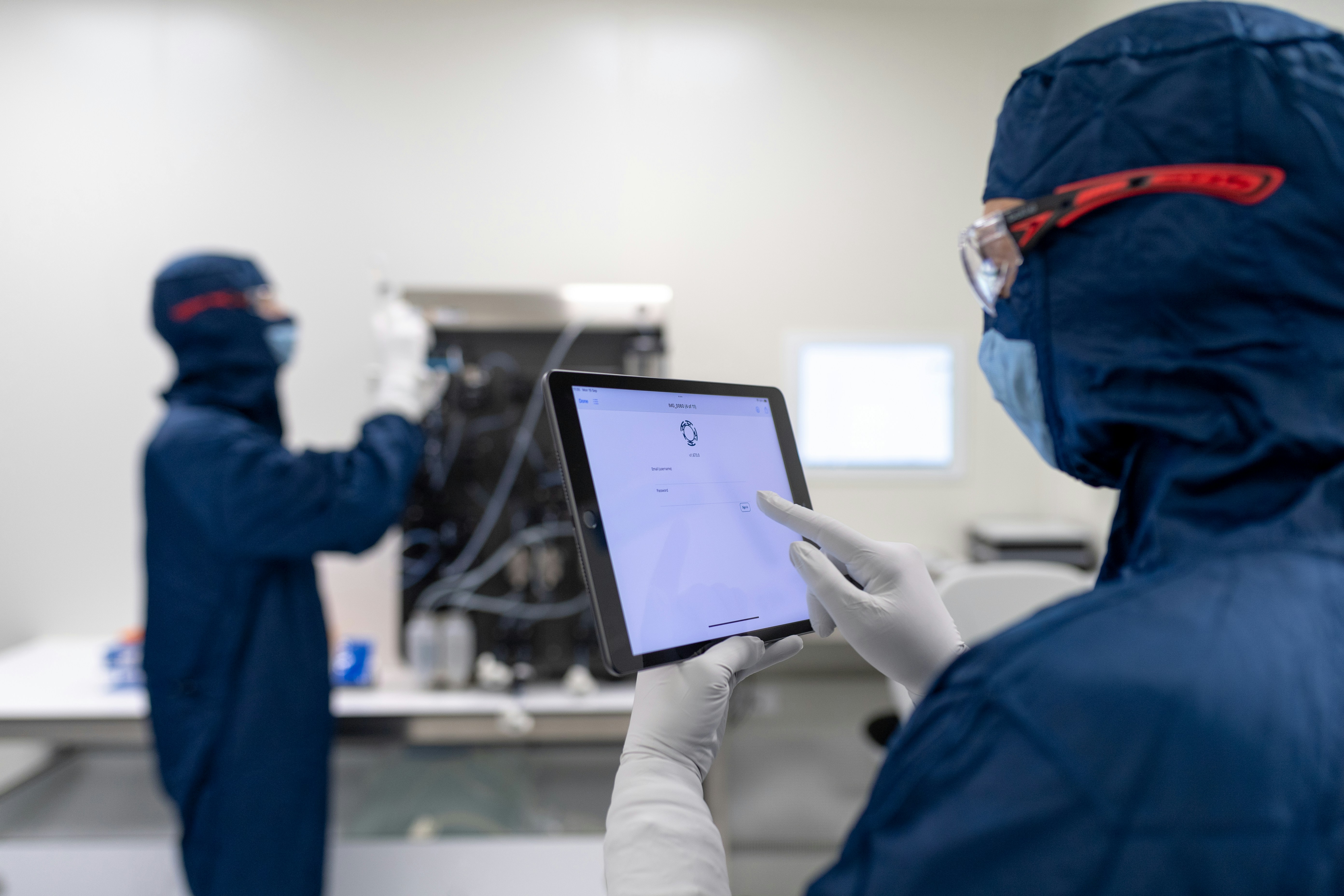 a few people in blue lab coats working on a computer