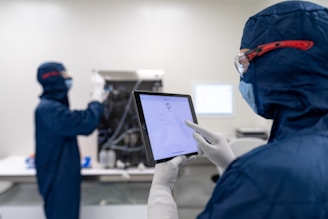 a few people in blue lab coats working on a computer