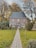 a brick building with a path and grass and trees around it