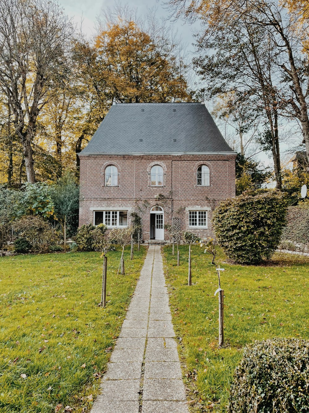 a brick building with a path and grass and trees around it