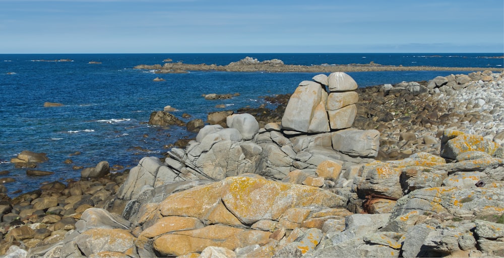 a rocky beach with a body of water in the background