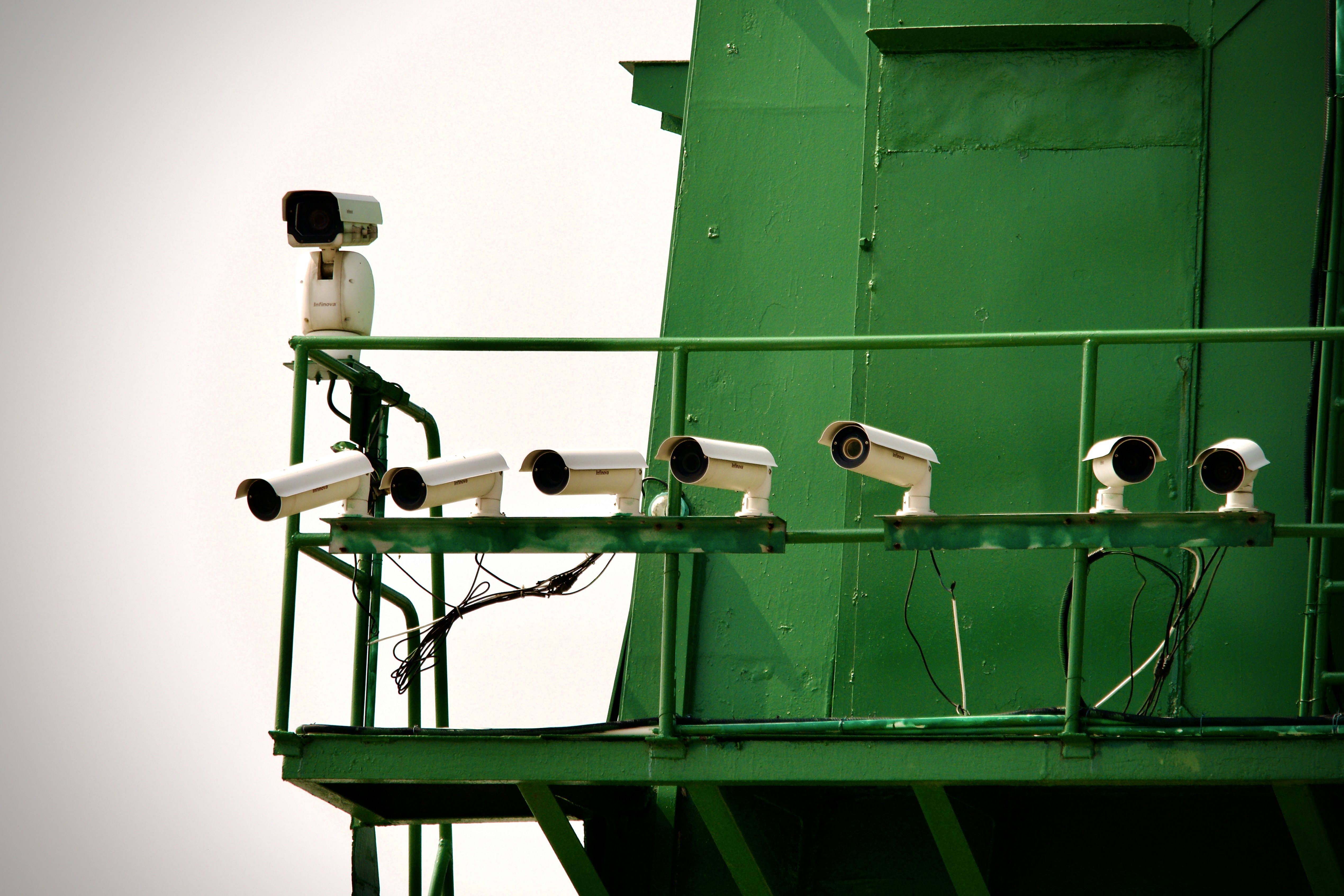 A team of IT professionals reviewing CCTV installation blueprints and discussing camera placement in a modern office conference room.