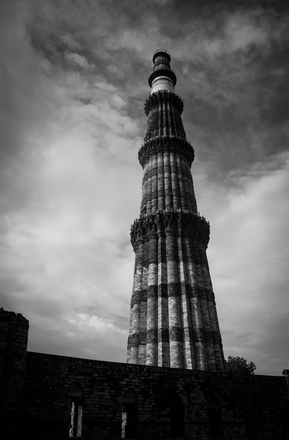 a tall tower with a cloudy sky with Qutub Minar in the background