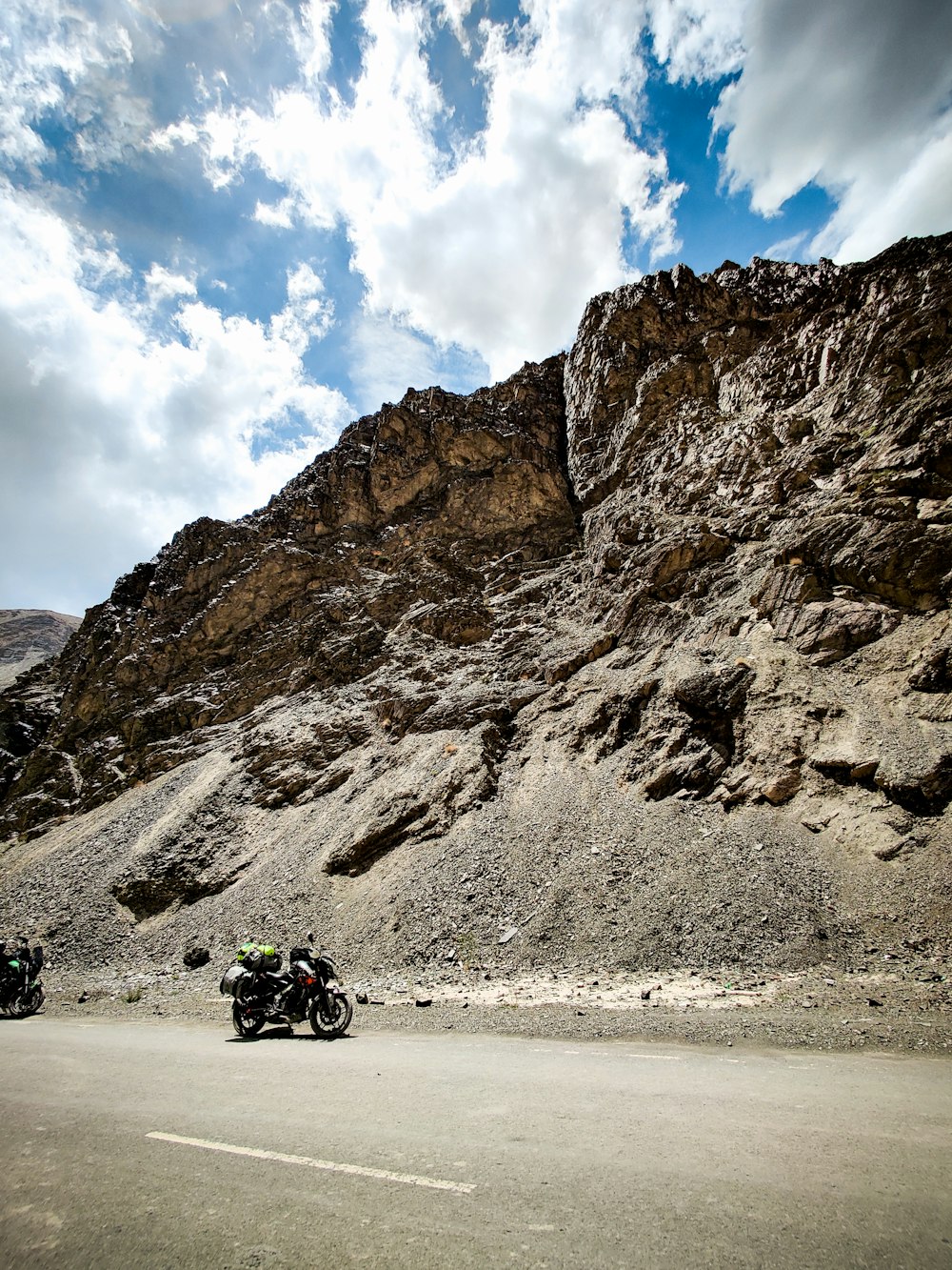 a group of motorcycles parked on a road next to a large rock