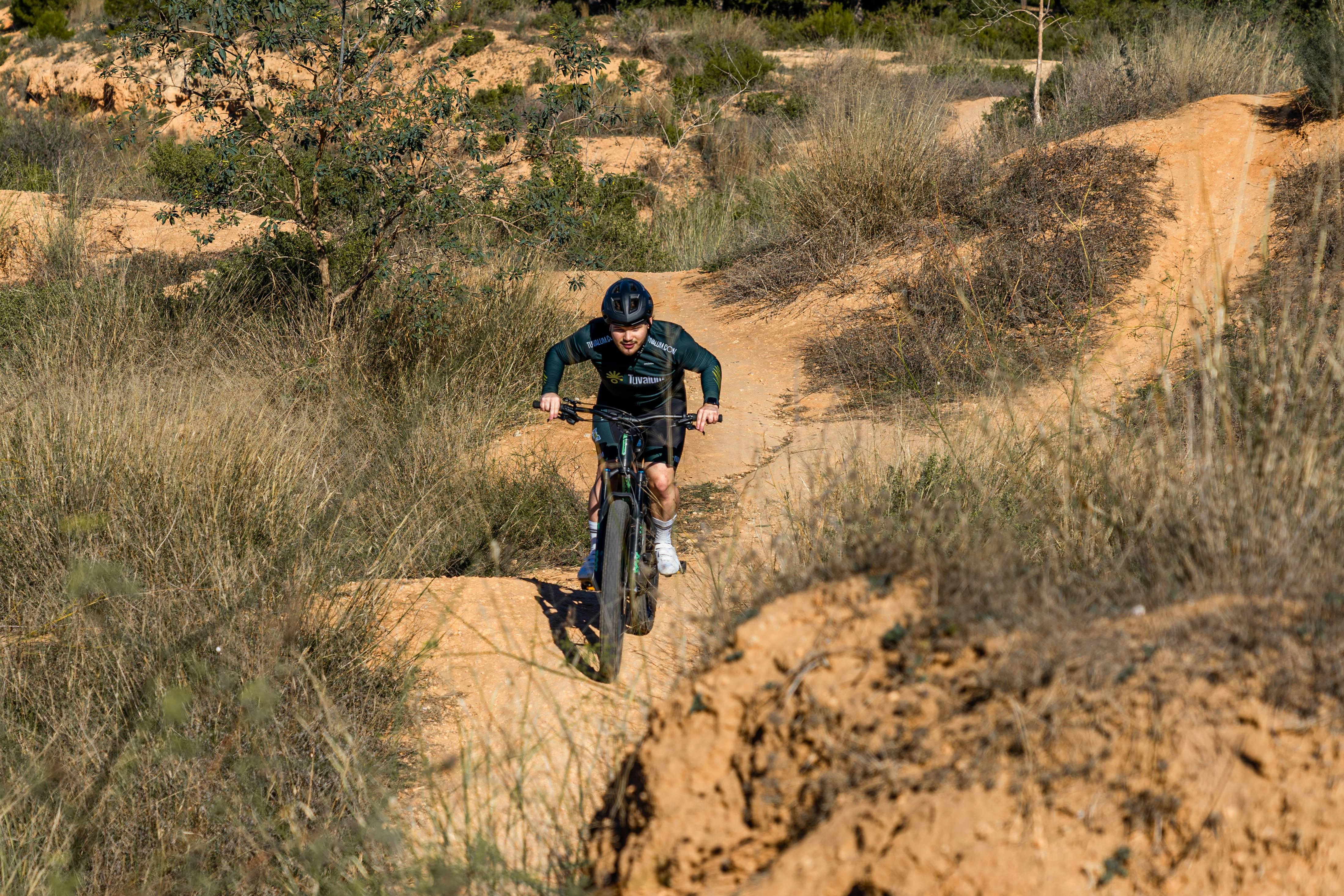 a person riding a bike on a dirt path in the woods, 