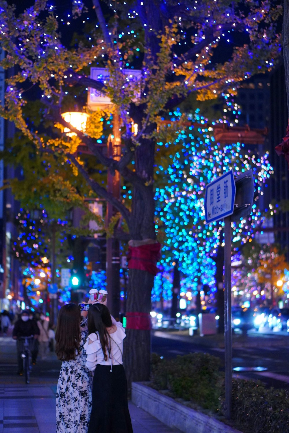 two women kissing under a tree