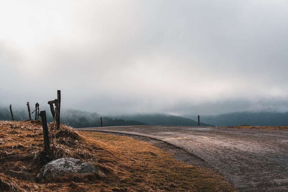 a dirt road with a fence and a hill with a tower in the distance