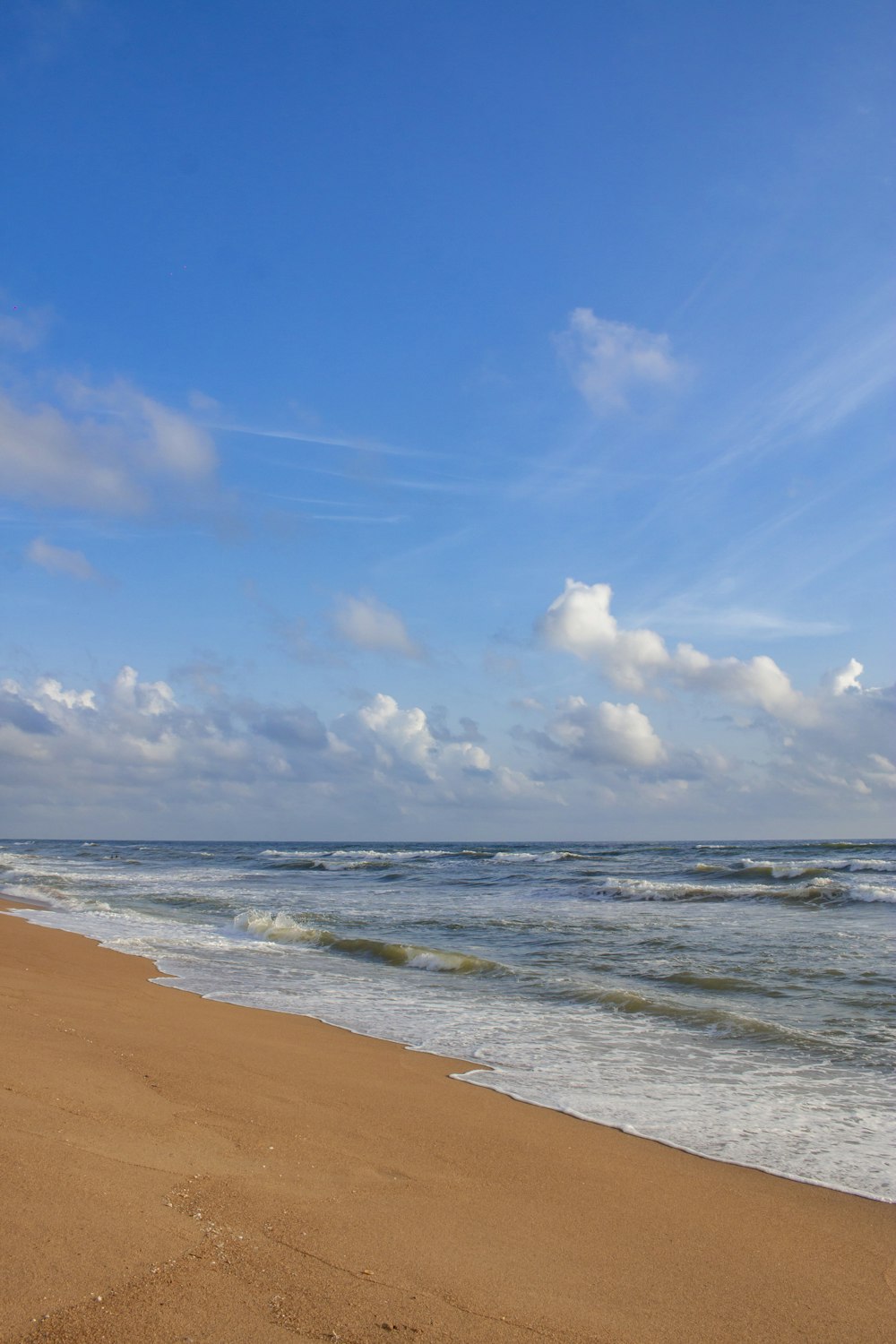 a beach with waves and blue sky