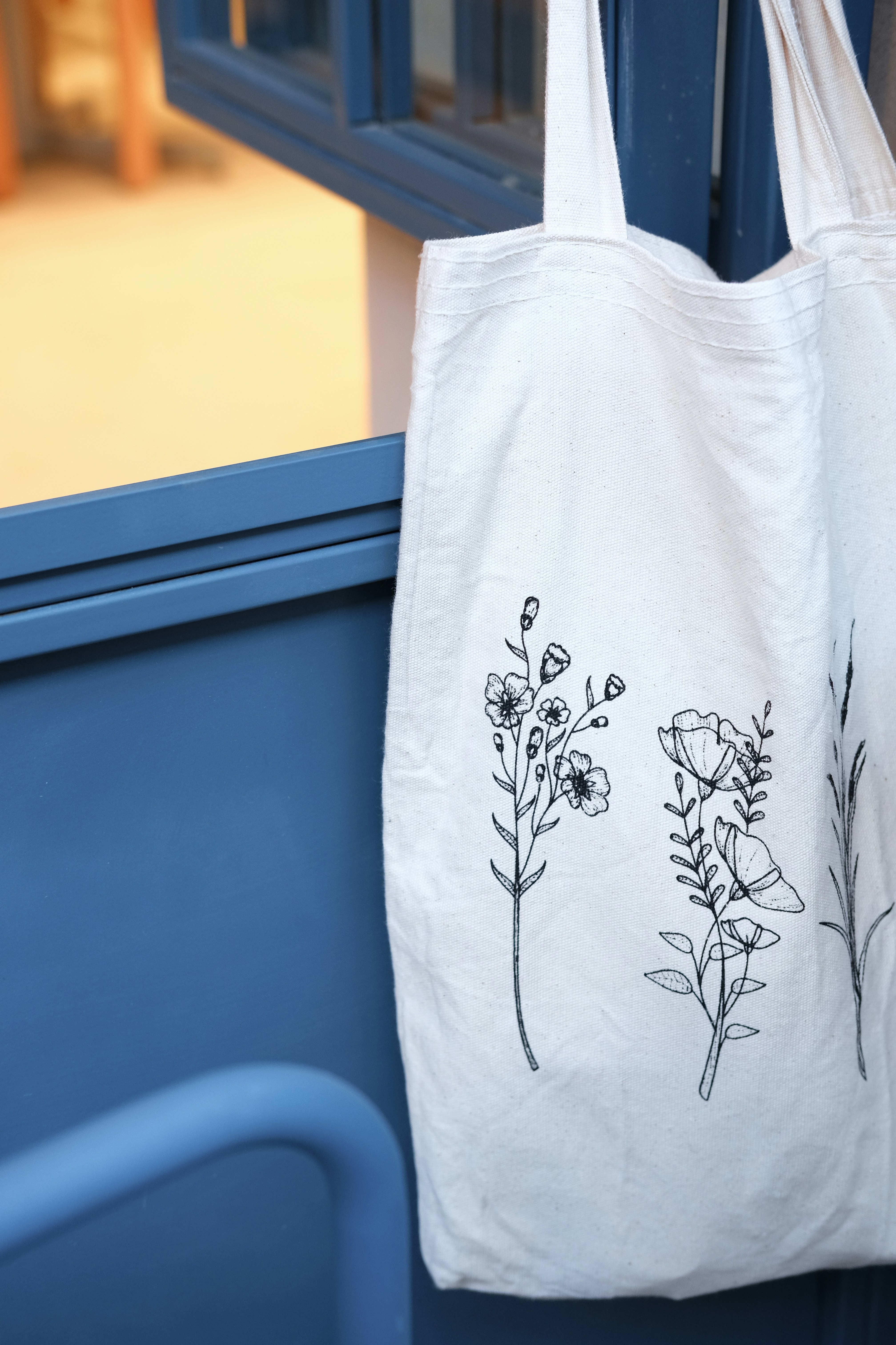 Canvas tote bag with colorful batik pattern in turquoise and gold on white background
