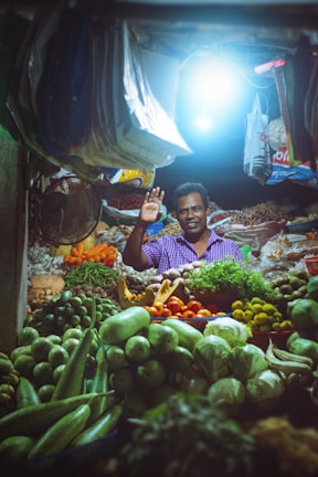 A candid moment of a local market vendor smiling warmly among colorful produce.