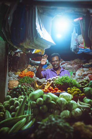 A smiling vendor proudly showcasing fresh local products from their small shop.