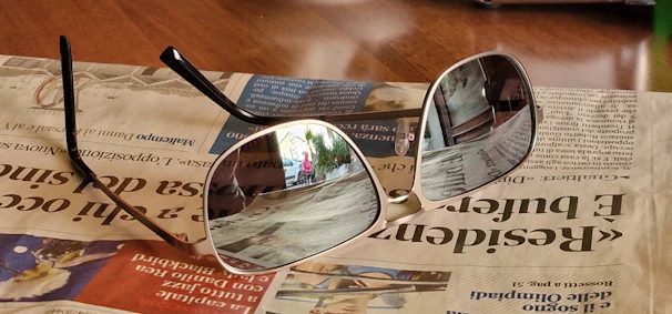 A stylish pair of sunglasses reflecting a sunny outdoor scene.