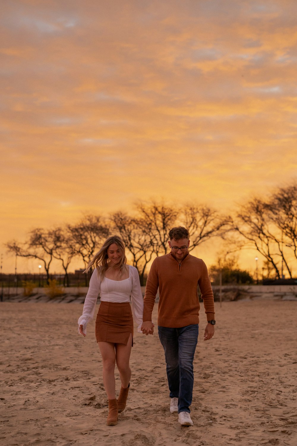 a man and woman walking on a dirt road with trees in the background