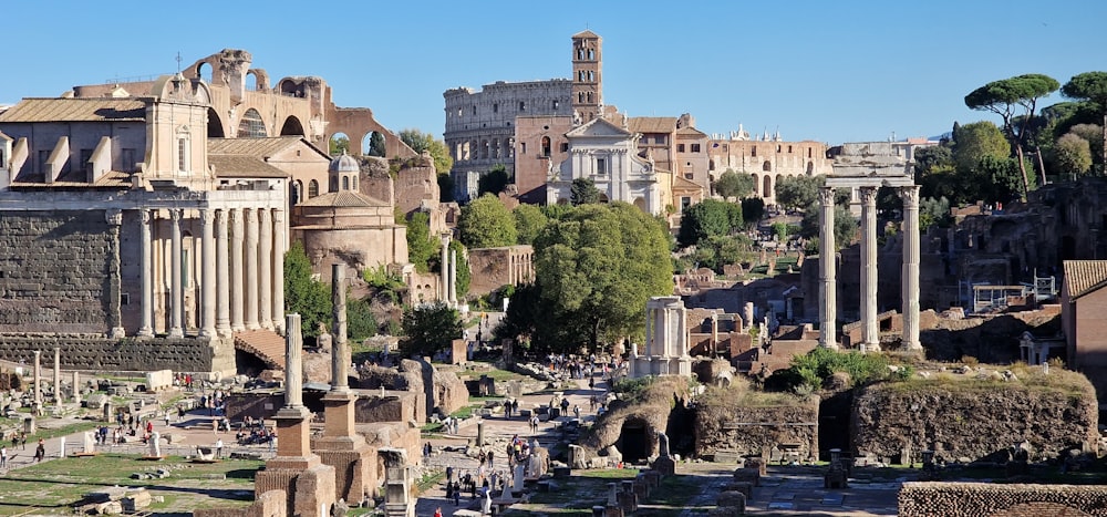 a large building with columns and a courtyard in front of it with Roman Forum in the background