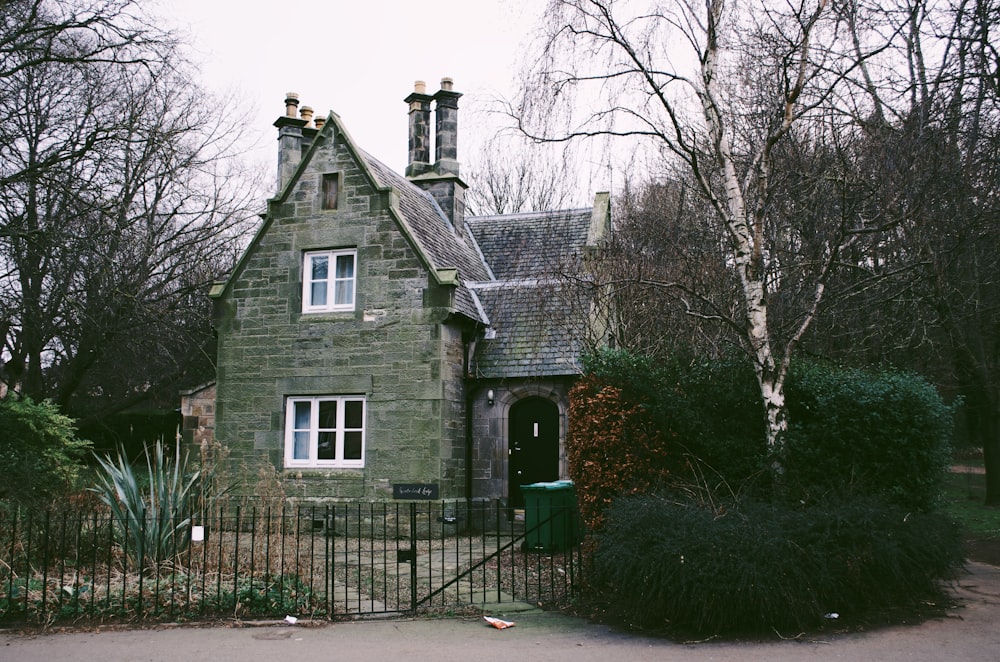 a house with a fence and bushes around it