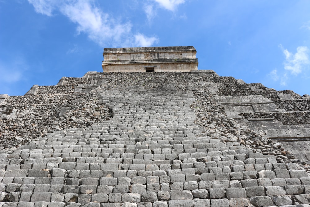 a stone pyramid with a stone walkway with Chichen Itza in the background