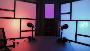 a table with a lamp and a chair in a room with windows