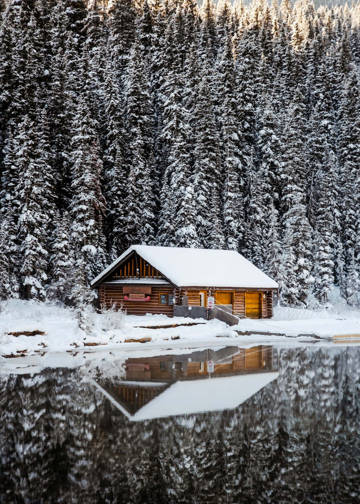 A cabin on a frozen lake surrounded by snow-covered trees in winter